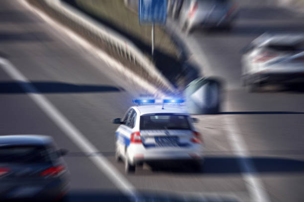 coche de policía con luces azules que se mueven rápidamente en el entorno urbano del tráfico. - social security flash fotografías e imágenes de stock