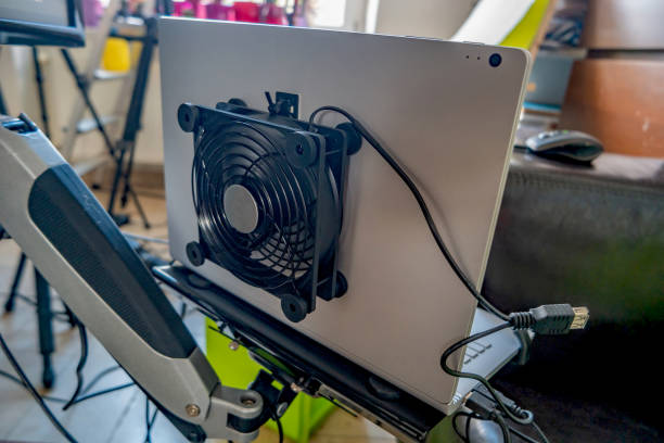 istock External computer fan is attached to the rear side of the laptop for better cooling during intensive work and hot weather at home office. Concept of technological lifehack. 1363424744