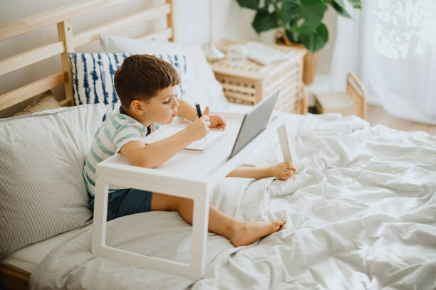 istock Little toddler boy sitting on bed and learning how to write letters 1363424926