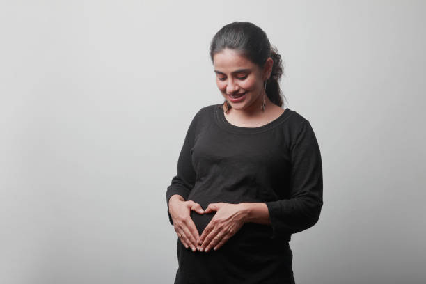 Young woman expecting a baby affectionately touches her tummy stock photo