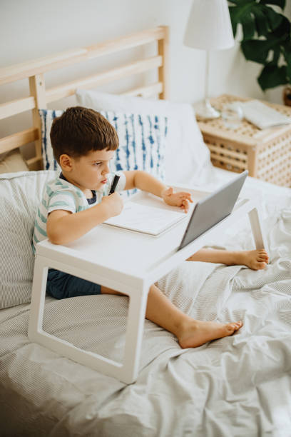 istock Little toddler boy sitting on bed and learning how to write letters 1363425601