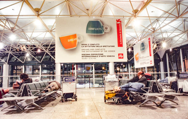 advertising for the biennale in Venice at airport Fiumicino in Rome. Due to a streik, people have to overnight at the benches in the airport Rome, Italy - August 3, 2008: advertising for the biennale in Venice at airport Fiumicino in Rome. Due to a streik, people have to overnight at the benches in the airport. venice biennale stock pictures, royalty-free photos & images
