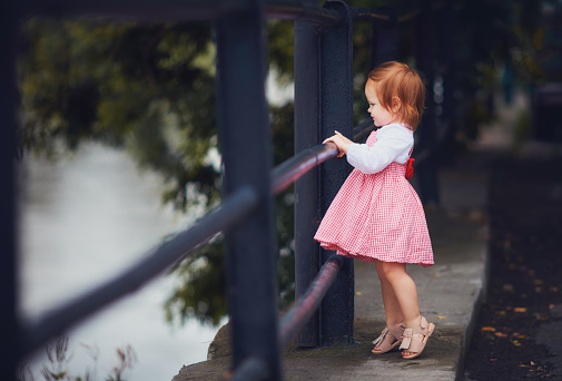 adorable baby girl in fluffy summer dress and sandals on the walk. one and a half year old baby