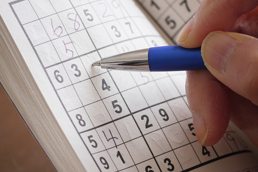 Close-up of hand to fill in Sudoku puzzle with a ballpoint pen