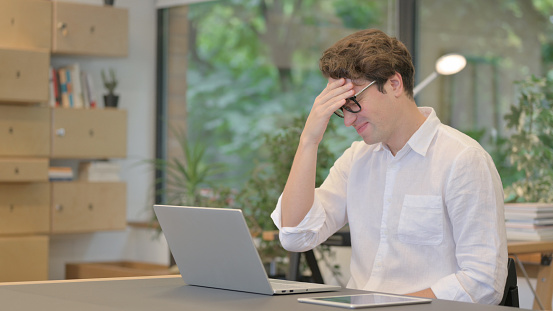 Man Reacting to Loss While using Laptop in Modern Office