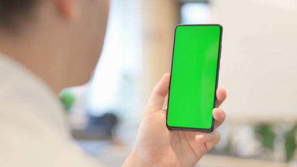 istock Young Man Looking at Smartphone with Green Chroma Screen 1363435406