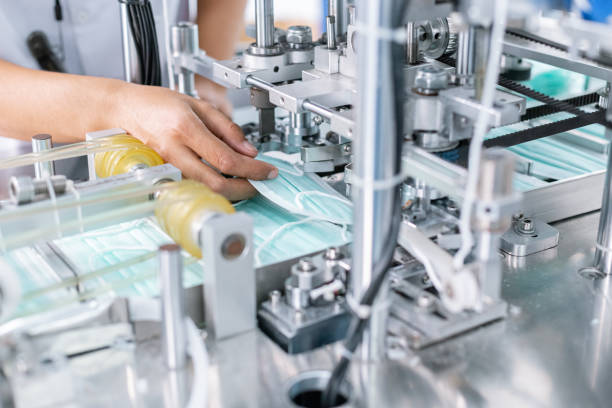 istock Hand of functionary worker take hygienic face mask in machine production, Mask manufacturing factory. 1363437635