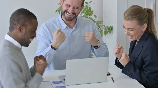 istock Cheerful Business People Celebrating Success while using Laptop in Office 1363437808