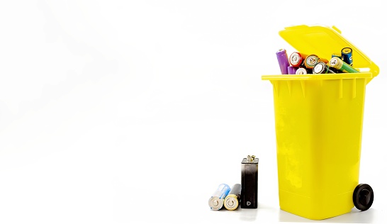 Yellow urban container, suitable for recycling used batteries on white background, waste recycling concept, copy space