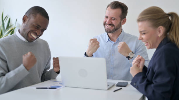 istock Cheerful Business People Celebrating Success while using Laptop in Office 1363440098