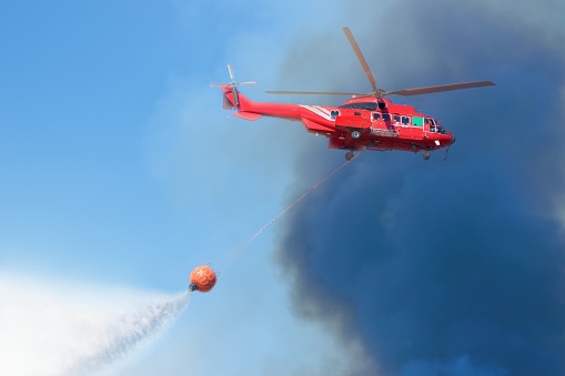 Firefighter rescue helicopter with helitanker droping water