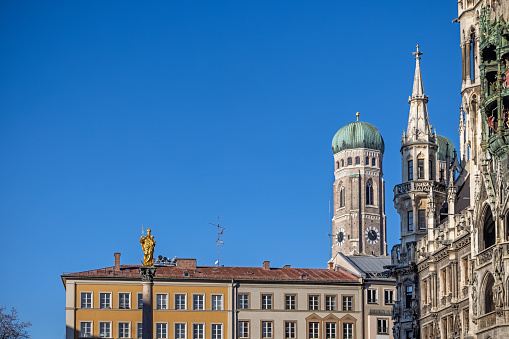 Large blue sky with a view to one of the towers of the cathedral and part of the façade of the town hall of the German city Munich which is the capital city in Bavaria