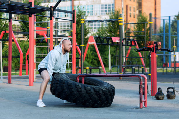 istock A man with a beard and interesting hairstyle does the tire press exercise (edging a heavy big tire) 1363444814