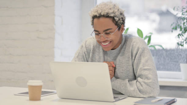 istock African Woman Celebrating Success while using Laptop in Office 1363451916