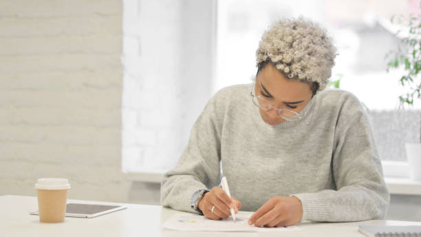 istock African Woman Writing on Paper in Office 1363452314