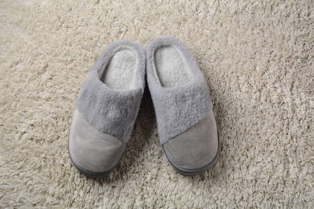 istock A female warm slippers on grey mat. Pair of comfortable slippers 1363457849