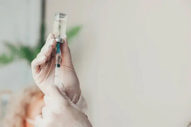 Photo of Doctor's hands holding a syringe with Coronavirus vaccine. Covid-19 Vaccination. Medical treatment. Virus protection.