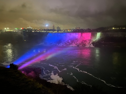 American falls on the Niagara River lighted up with red, white and blue spot lights from the Canadian side of the river
