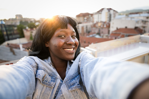 Young African American woman on balcony taking selfie