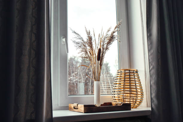 istock Using dried natural various grass plants inside vase indoors for home decoration. Vase with various plants and wood black metal wire lantern on window sill in daylight. 1363461467