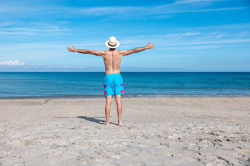 Happy successful man at seaside in Cornwall raising arms