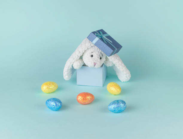istock Scattered Easter eggs and a white rabbit in a gift box on a blue background. 1363464318