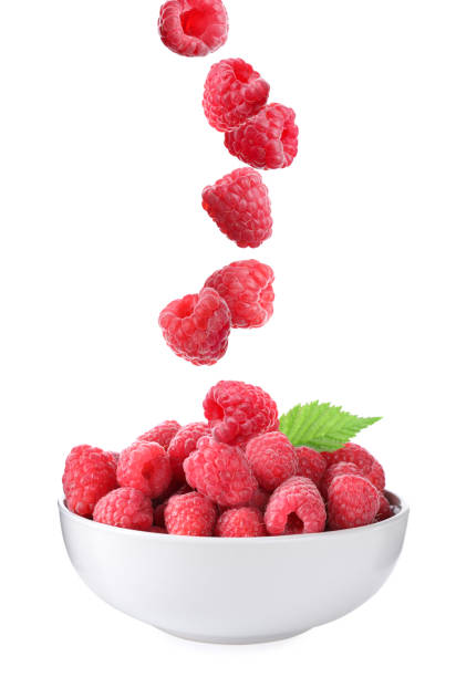 istock Fresh ripe tasty raspberries falling into bowl on white background 1363467921