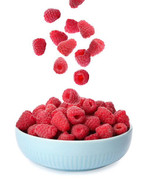 istock Fresh ripe raspberries falling into bowl on white background 1363468183