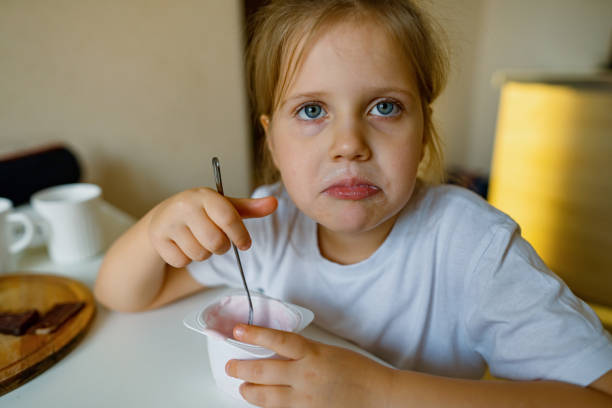 istock Cute girl eats yogur, has dirty mouth, has fun, grimaces 1363468312