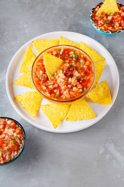 istock Salsa dip and nacho chips on a white plate. Tortilla chips and salsa sauce in bowl on a gray background. Mexican cuisine. Top view. Copy space 1363469304