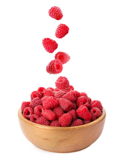 istock Fresh ripe raspberries falling into bowl on white background 1363469313