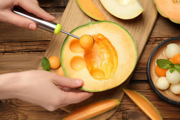 mujer haciendo bolas de melón en la mesa de madera, primer plano - melon balls fotografías e imágenes de stock