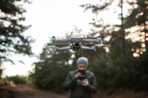 il pilota dell'uomo sta pilotando un drone con telecomando - pilotando foto e immagini stock