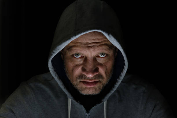 istock A man in a hood, a lighted face on a dark background. 1363470670