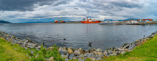 Panoramic view over cargo and cruise tour ships at Ushuaia harbor in Tierra del Fuego National Park at sunset, Patagonia, Argentina, golden Autumn