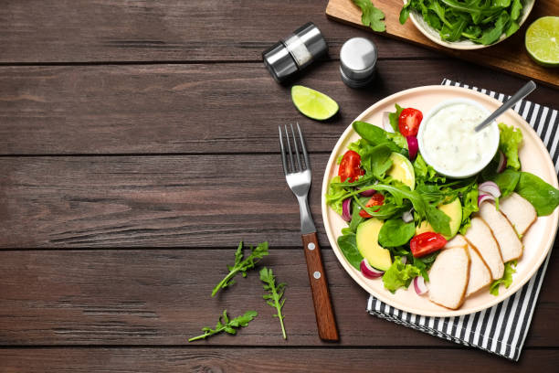 istock Delicious salad with chicken, arugula and avocado on wooden table, flat lay. Space for text 1363471847