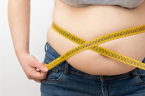 Mujer que mide su porcentaje de grasa corporal con cinta métrica photo