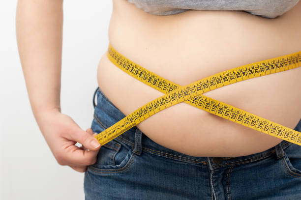 Woman measuring her body fat percentage with tape measure Woman measuring her body fat percentage with tape measure for fat or obesity background excess fat stock pictures, royalty-free photos & images