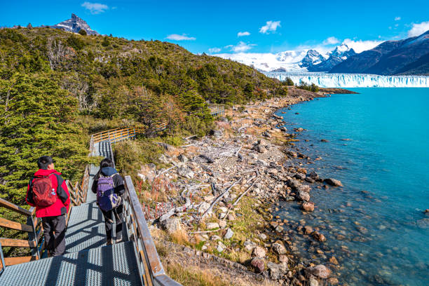 dos excursionistas y sendero para caminar en el lago argentino cerca del enorme glaciar perito moreno en la patagonia en otoño dorado, américa del sur - patagonia el calafate horizontal argentina fotografías e imágenes de stock