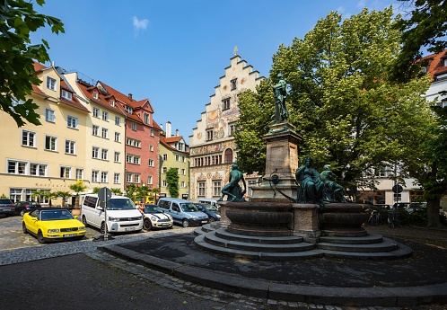 Lindau, Germany, July 6, 2015: View of the Reichsplatz Square with the Old Town Hall (painted building, German: Altes Rathaus) in this Bavarian town on a sunny summer day. In the foreground is the fountain Lindaviabrunnen.