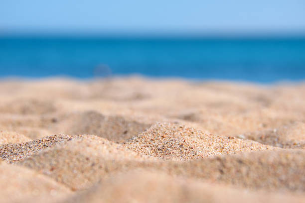 istock Close up of clean yellow sand surface covering seaside beach with blue sea water on background. Travel and vacations concept. 1363473237
