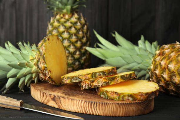 istock Cut fresh pineapples on black wooden table 1363475227