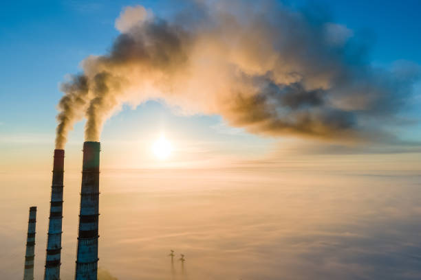 vista aérea de canos altos de usinas de carvão com fumaça preta subindo a atmosfera poluidora ao pôr do sol. - rasto de fumo de avião - fotografias e filmes do acervo