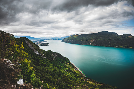 Color landscape photography of a high angle view over Bourget Lake by a cloudy dramatic sky in summer. This image was taken on Bourget Lake riverbanks, near Aix-Les-Bains famous thermal station city in Savoie, Auvergne-Rhone-Alpes region in France, Europe.