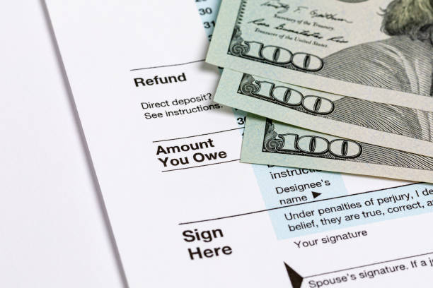 1040 individual income tax return form and money. Tax payment, filing taxes and financial planning concept stock photo
