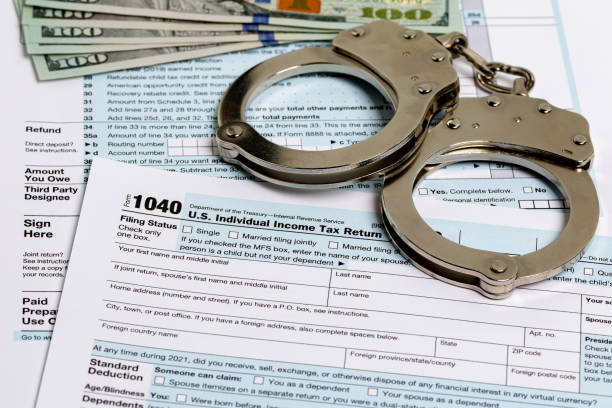 Income tax return documents and handcuffs. Tax evasion, crime and fraud concept. stock photo