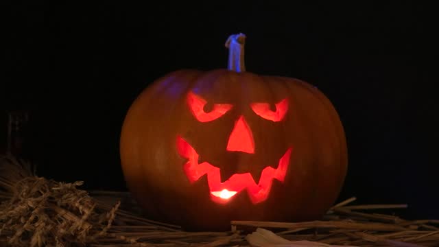 Halloween pumpkin with burning candle at dark,  halloween holiday