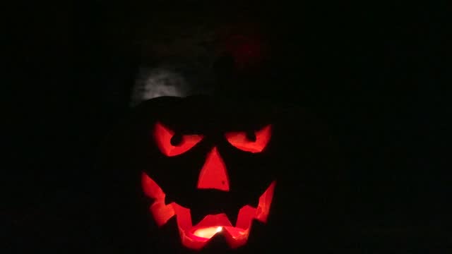 Halloween pumpkin with burning candle at dark,  halloween holiday