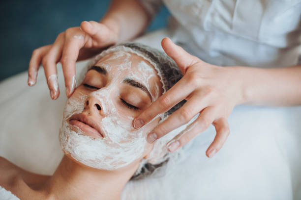 Closeup portrait of cosmetologist's hands applying mask on client's face in spa salon. Natural beauty. Facial skincare. Rejuvenation treatment. stock photo