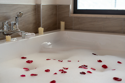 Bubbling water in hot tub with decorated rose petals. Romantic atmosphere of a hot tub bath